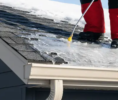 Ice dam removal technician using a steam wand to melt thick ice buildup on a residential roof in New Haven, CT